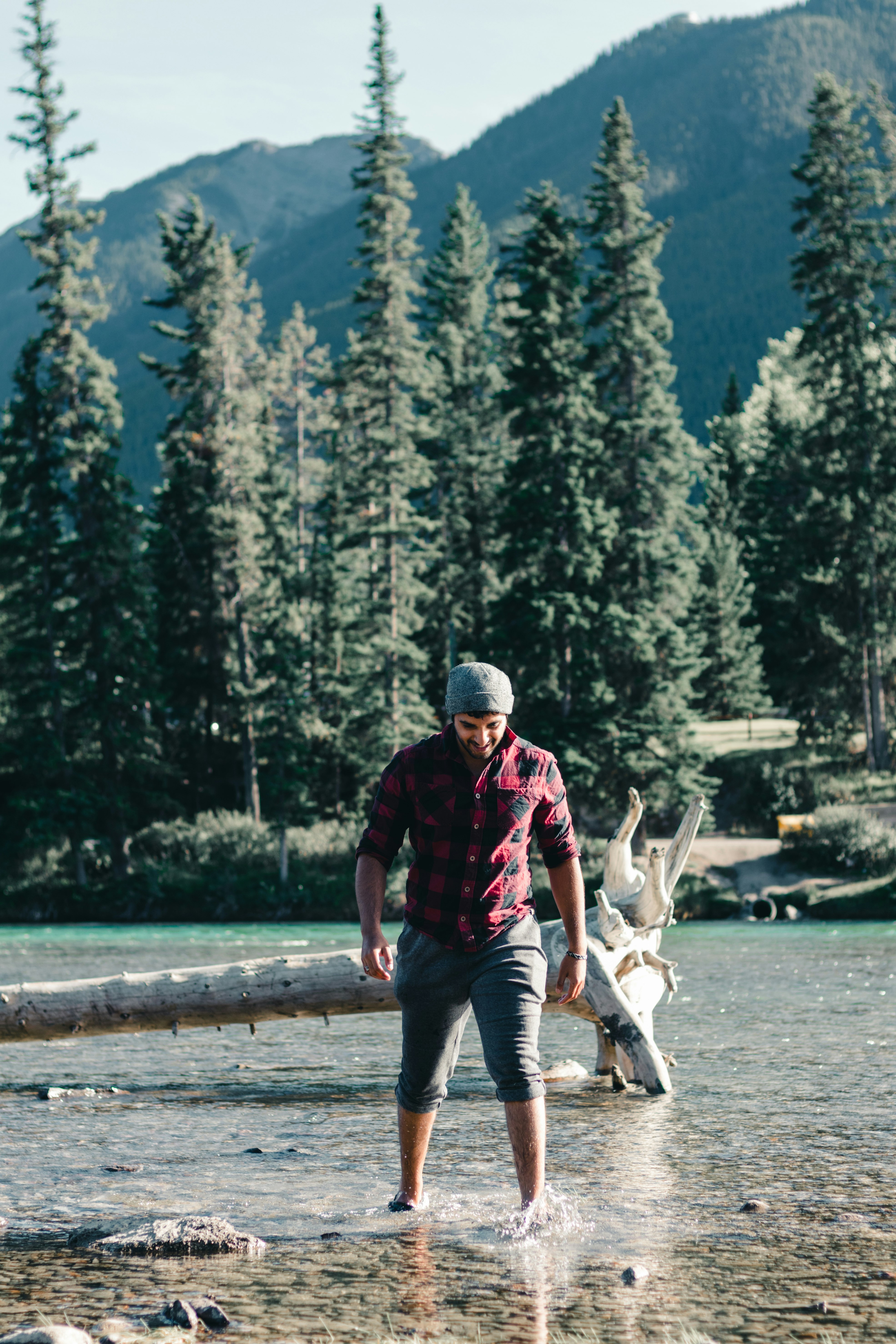 man in red and black jacket and gray denim jeans holding white dog